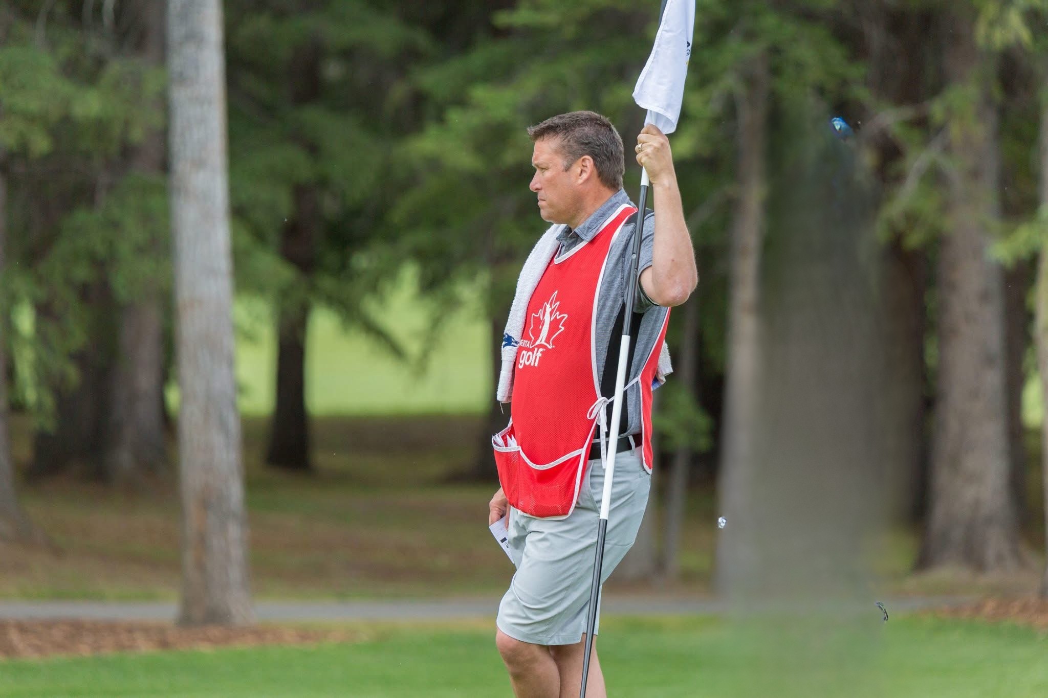 Dana Gorbahn caddying on the professional golf tour, holding the flag